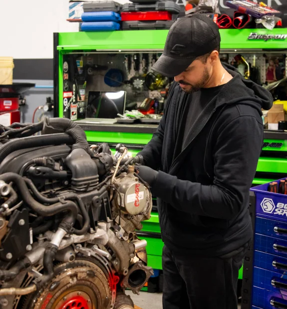 Acton Autowerks technician servicing a removed engine assembly in the workshop