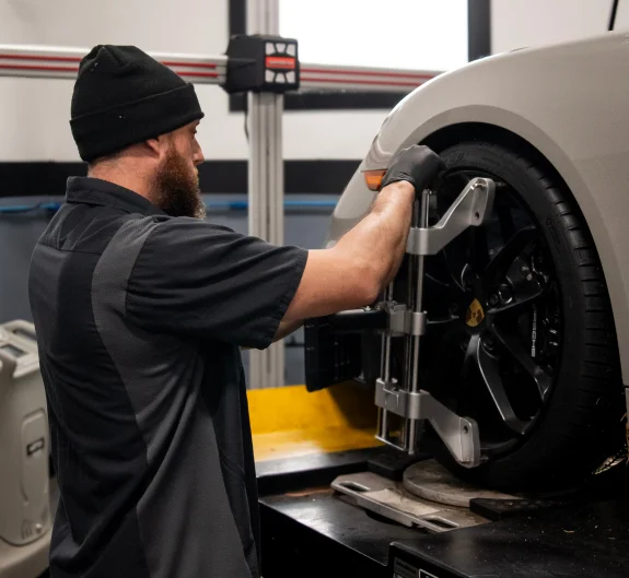Technician attaching a wheel alignment sensor to a silver vehicle