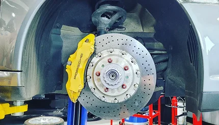 Drilled performance brake rotor and yellow caliper on a silver Porsche